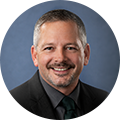 Brian Engle from Amphenol Advanced Sensors in front of a plain blue circular background
