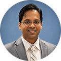 Niranjan Malvadkar Ph.D. Research Scientist at DuPont in front of a plain blue circular background